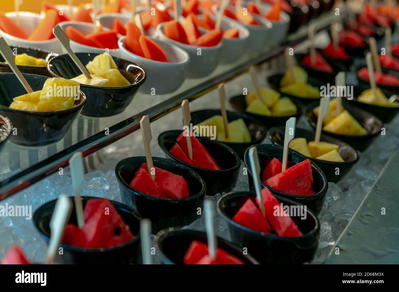 Ausgewähltes tropisches Fruchtbuffet bei Veranstaltungen im Restaurant. Catering-Essen. Frische Melone und Ananasscheiben in kleiner Schüssel auf zerkleinertem Eis. Stockfoto