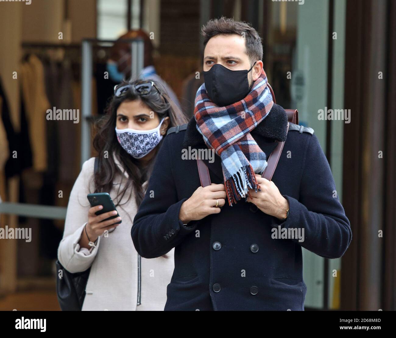 Ein Paar mit Gesichtsmasken geht entlang der Regent Street.Öffentliche Leute werden gesehen, wie sie Gesichtsmasken tragen, während sie in London einkaufen, nachdem Premierminister Boris Johnsons Ankündigung eines neuen dreistufigen Schließsystems wegen der zunehmenden Fälle von Coronavirus-Infektionen in Großbritannien. Stockfoto
