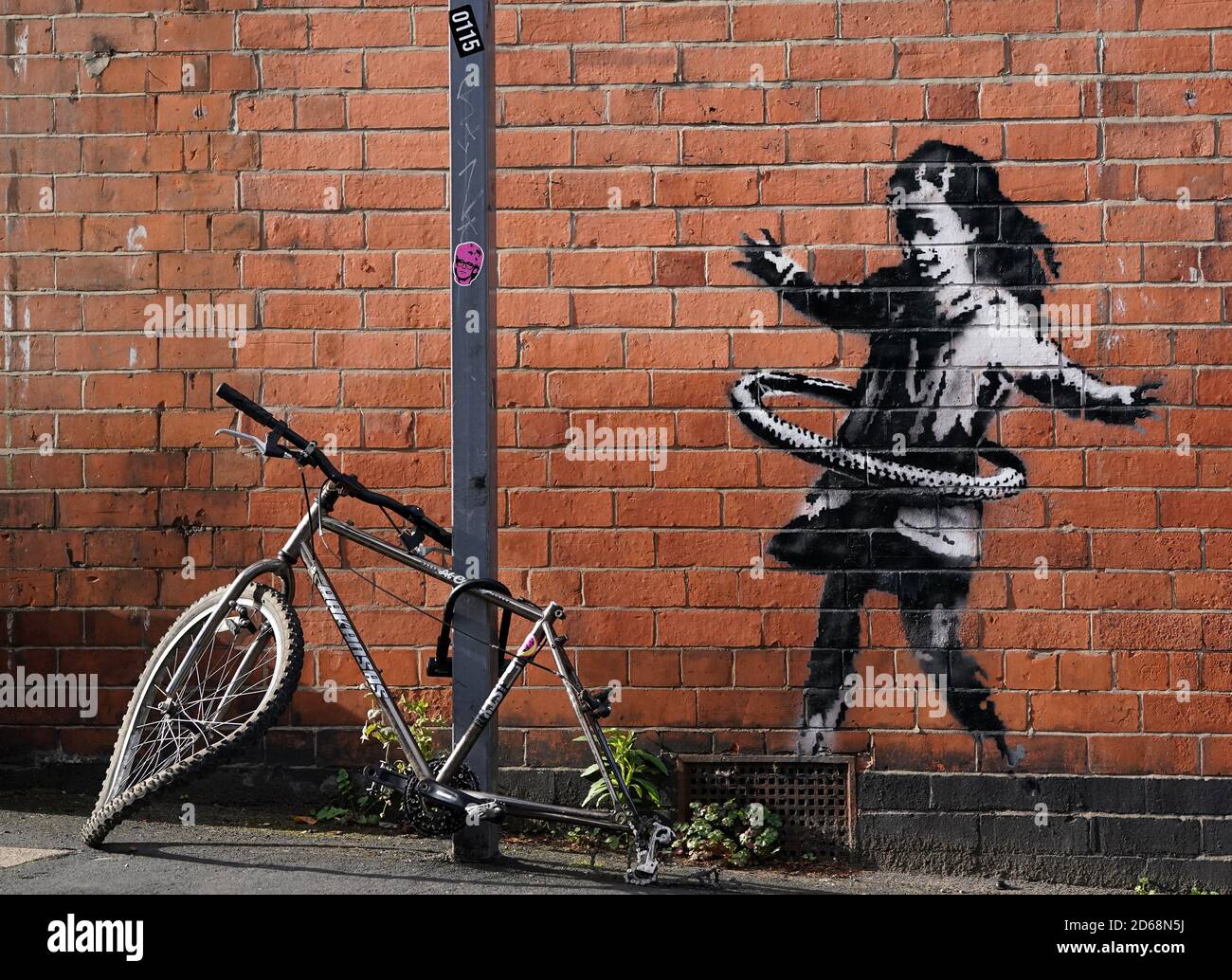 Graffiti-Kunstwerke, die jetzt als das Werk des Straßenkünstlers Banksy bestätigt wurden, befinden sich auf einer Seite eines Grundstücks an der Rothesay Avenue und der Ilkeston Road, Nottingham. Das Kunstwerk zeigt ein junges Mädchen, das mit einem Reifen spielt, und ist auf einer Wand in der Nähe eines verlassenen Fahrrads gemalt, dem ein Rad fehlt. Stockfoto