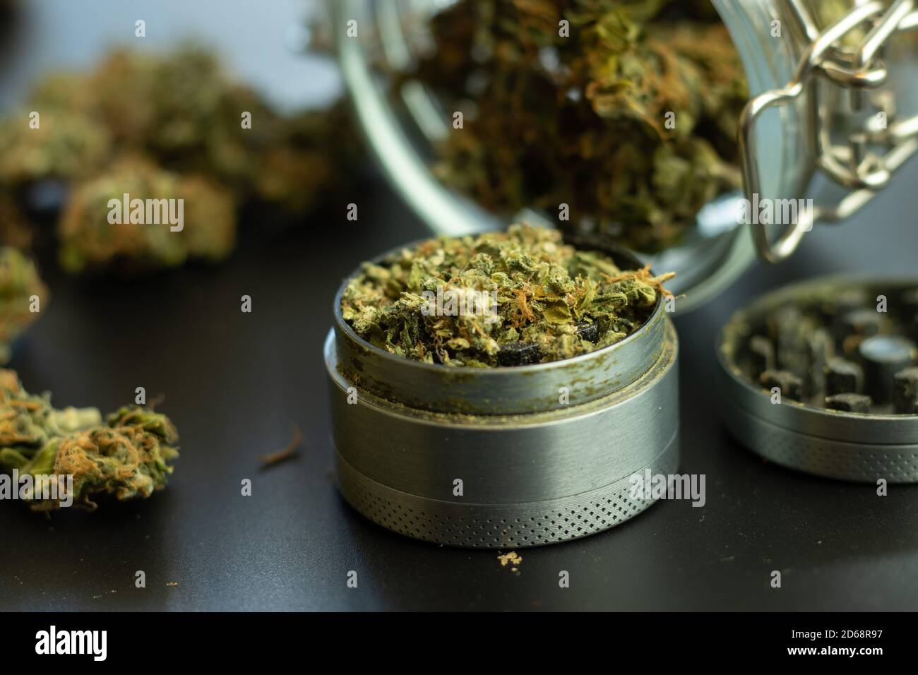 Grinder mit Marihuana Nahaufnahme. Cannabiskonsum im Gesundheitswesen. Verschwommener Hintergrund mit Unkrautknospen Stockfoto