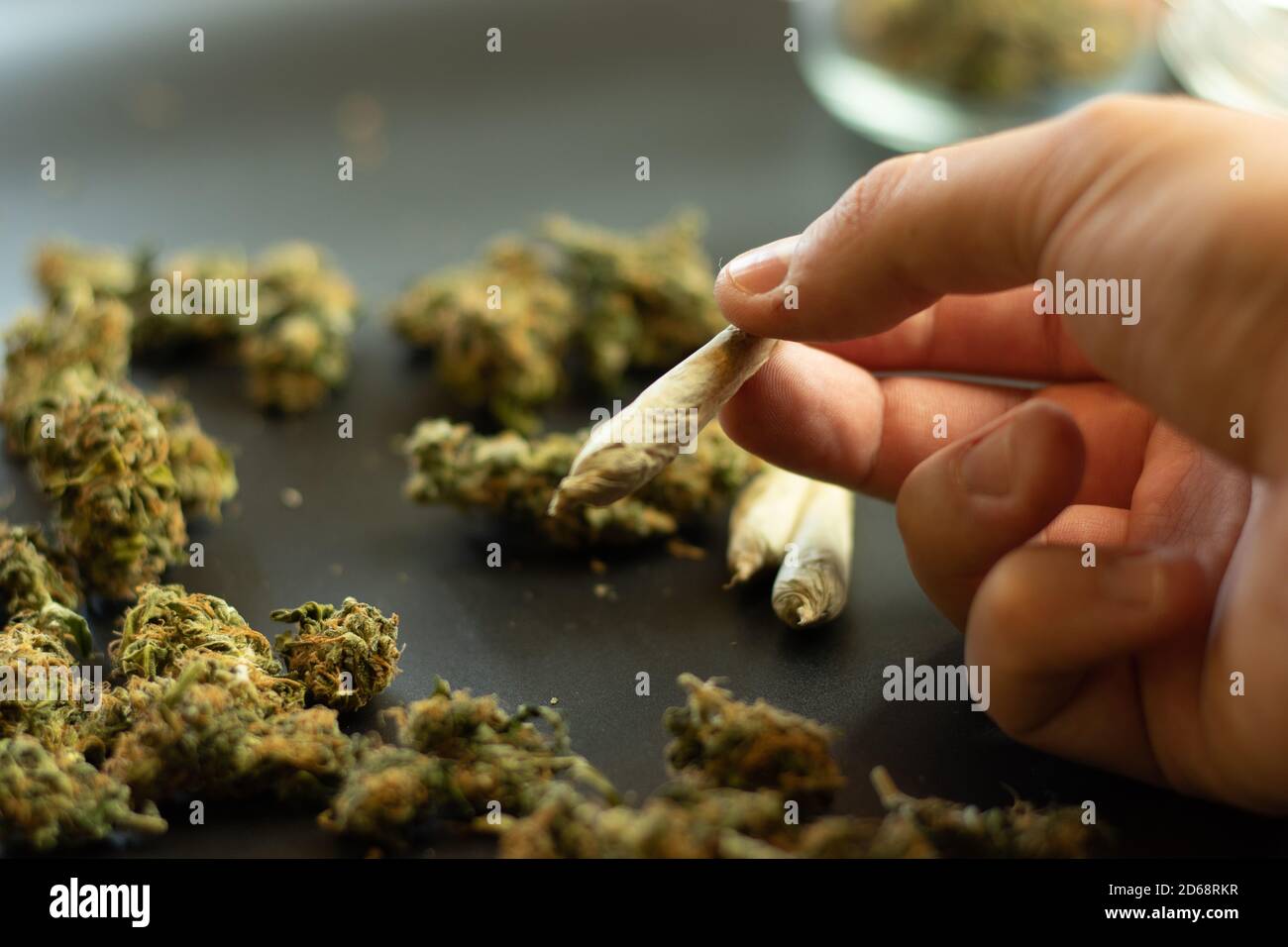 Drogenabhängigkeit Konzept, Mann hält Marihuana Joint in der Hand. Kopieren Raum Hintergrund mit Cannabis Knospen. Unkraucherprogramm Stockfoto
