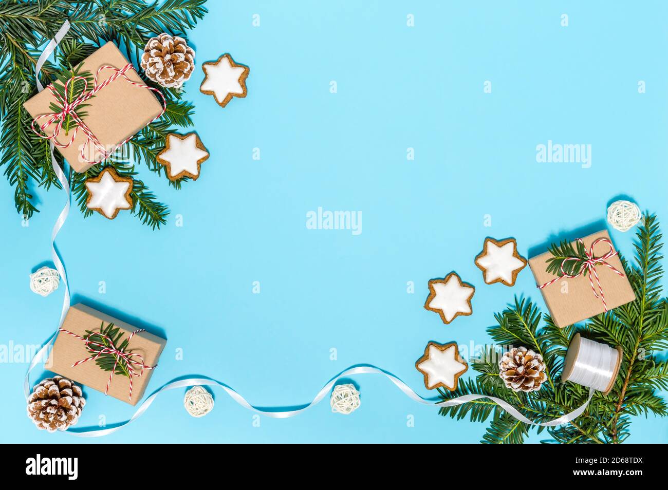 Plastikfreies Weihnachts-Flatlay mit Geschenkschachteln, Band und Feiertagsdekoration: Nadelbaum Ast, Zapfen, Zimt-Stern-Kekse auf blauem Hintergrund Stockfoto
