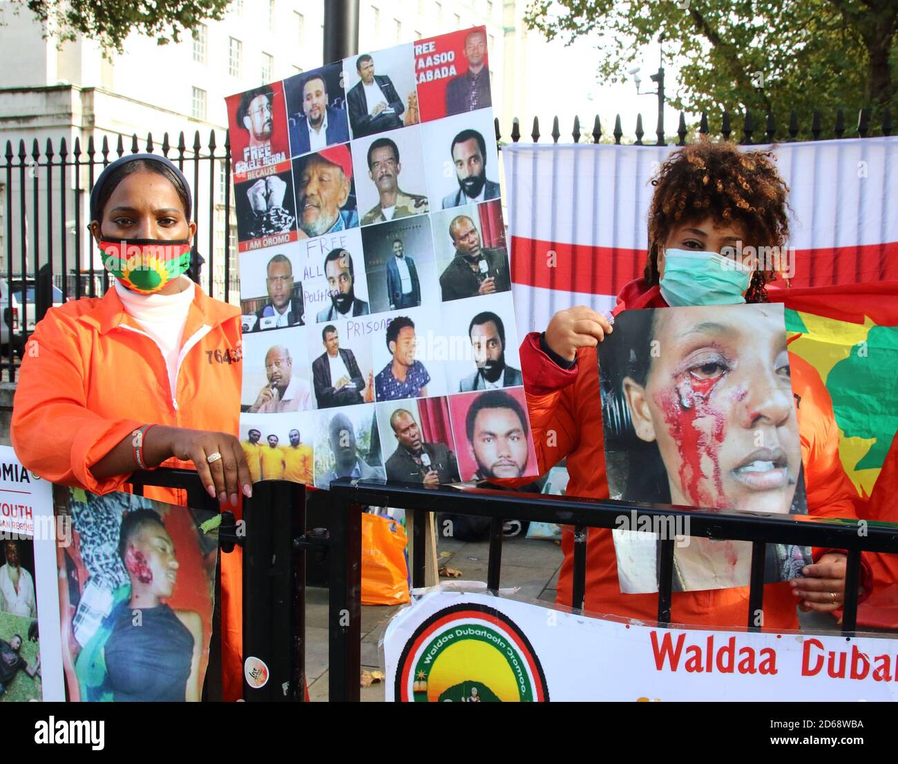 Zwei in London lebende Oromo-Frauen mit Gesichtsmasken zeigen Plakate mit Porträts ihrer Menschen, die in ihrer Heimat misshandelt werden.Oromo-Frauen in Großbritannien protestieren vor der Downing Street gegen den Missbrauch der Menschenrechte von Menschen in ihrer Heimat durch den äthiopischen Premierminister Abiy Ahmed. Oromia ist ein Bundesstaat in Äthiopien mit einer Bevölkerung, die fast der des Vereinigten Königreichs entspricht - 55 Millionen - und grenzt an Somalia, Südsudan und Kenia. Stockfoto