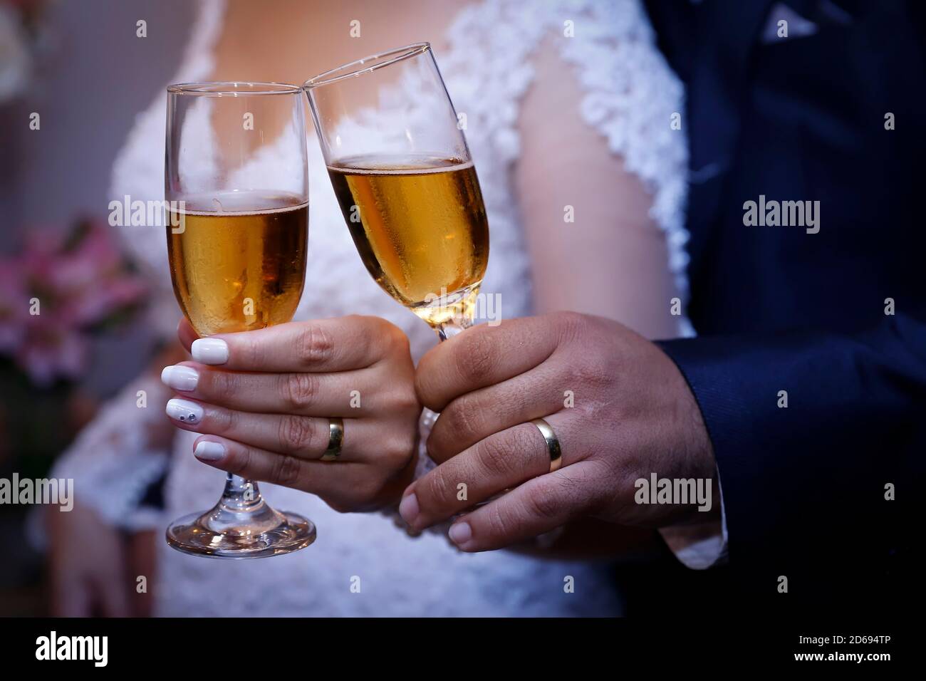 Detail Hände von Brautpaar tragen goldene Eheringe und Glasschüssel mit Alkoholgetränk Stockfoto