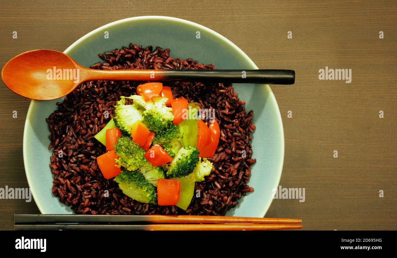 Schüssel mit schwarzem Reis auf dunkler Tischplatte. Draufsicht, horizontale Komposition, Kopierbereich. Stockfoto