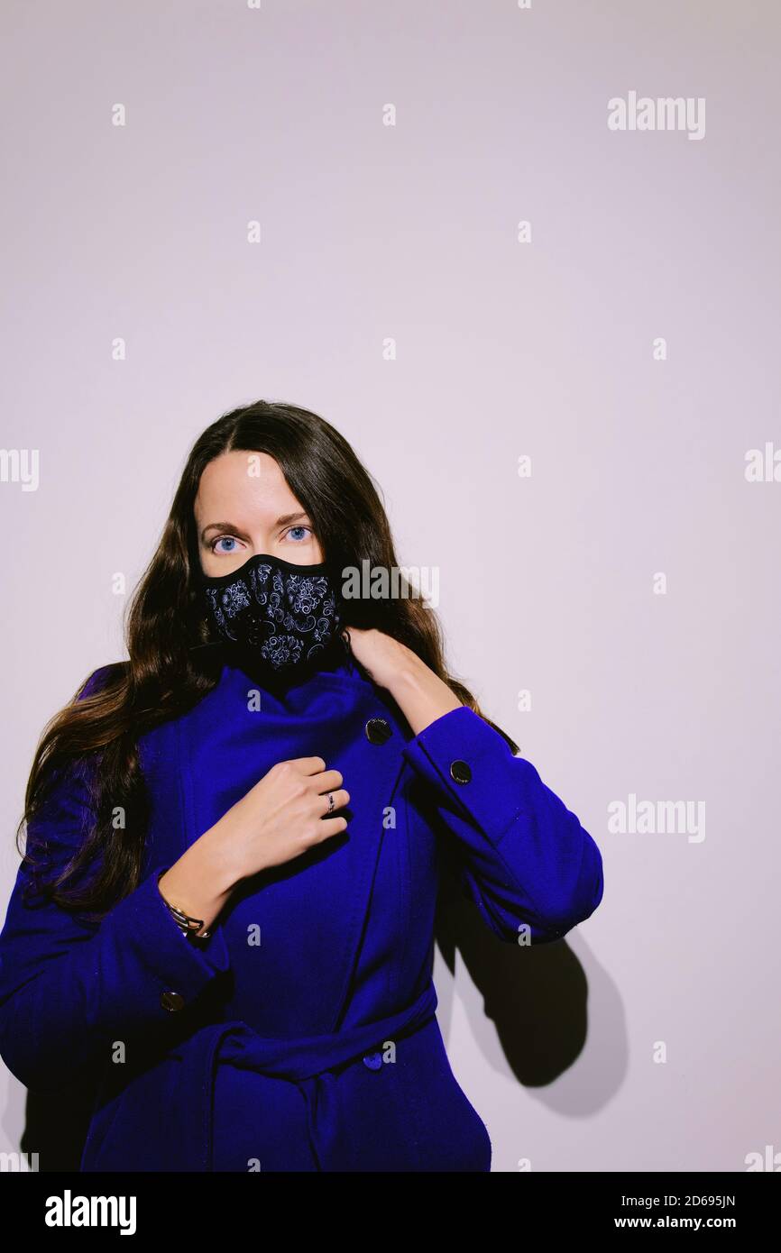 Portrait der schönen Frau mit blauen Augen tragen Schutzfilter N95 Stoff Gesichtsmaske. Attraktives Modell bereit, im Freien während Pandemie gehen. Stockfoto