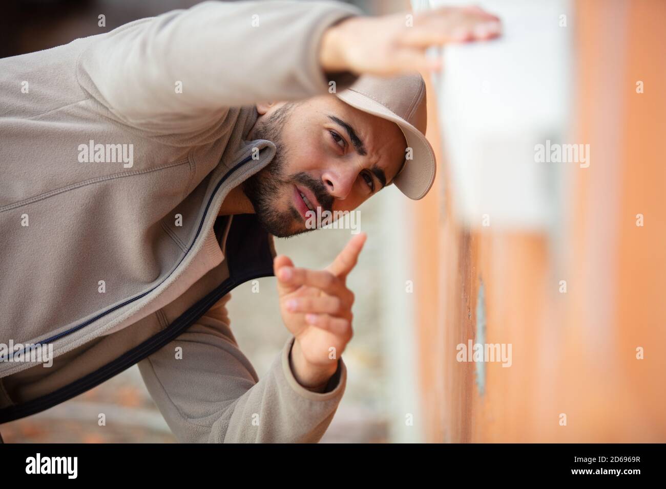 Ein Arbeiter mit einer Spitzenkappe, der die Fensterbank überprüft Stockfoto