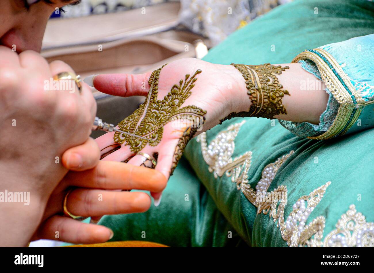 Eine Frau tätowierte die Hand der Braut mit Henna. Marokkanische Hochzeit. Die Traditionen des Maghreb Stockfoto