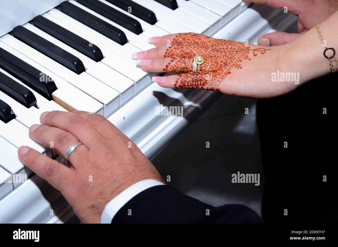 Arabische Jungvermählte spielen Klavier. Nahaufnahme der Hände mit Henna-Tattoo Stockfoto