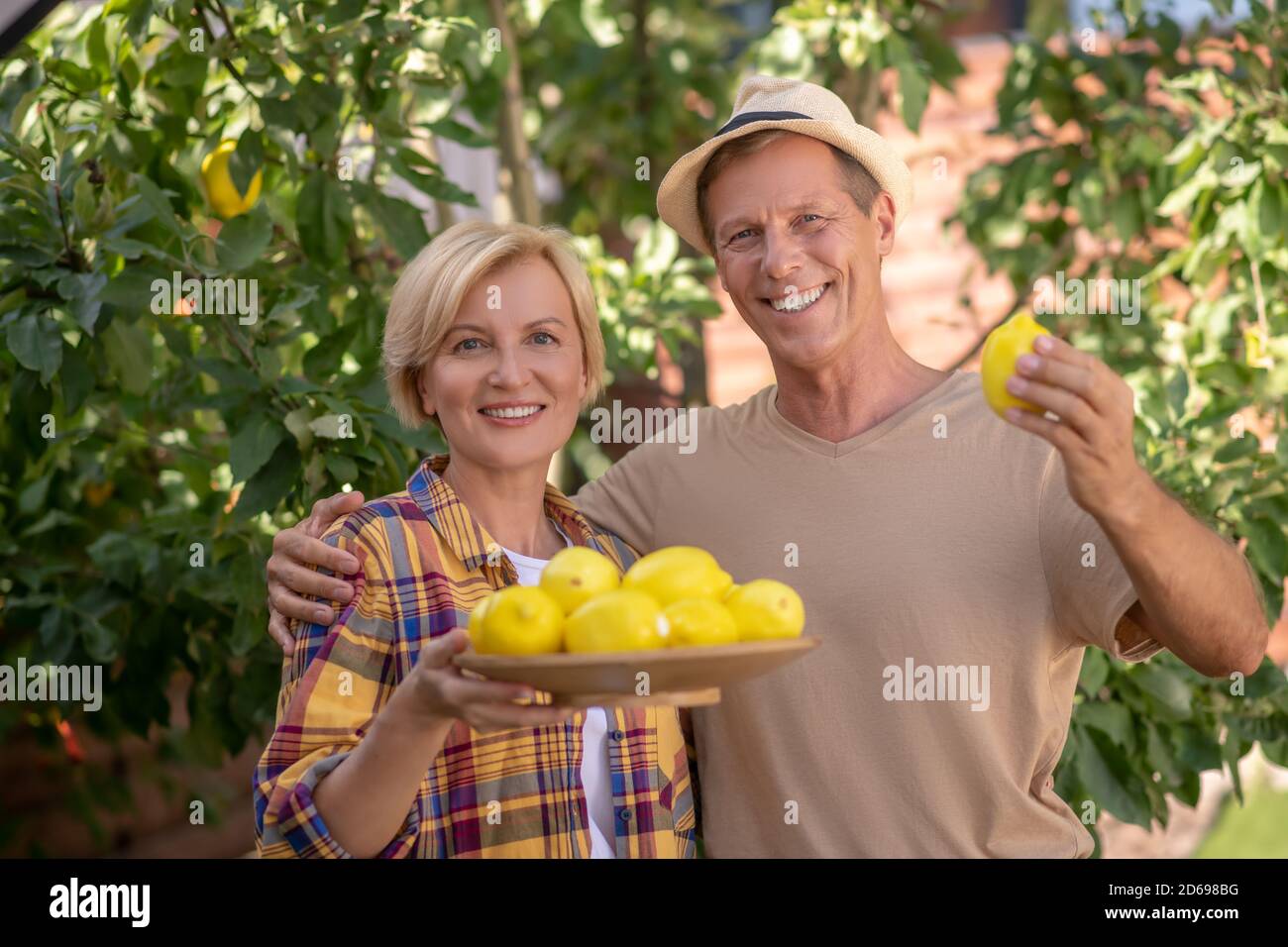 Glückliches Paar hält Teller mit Zitronen im Garten Stockfoto