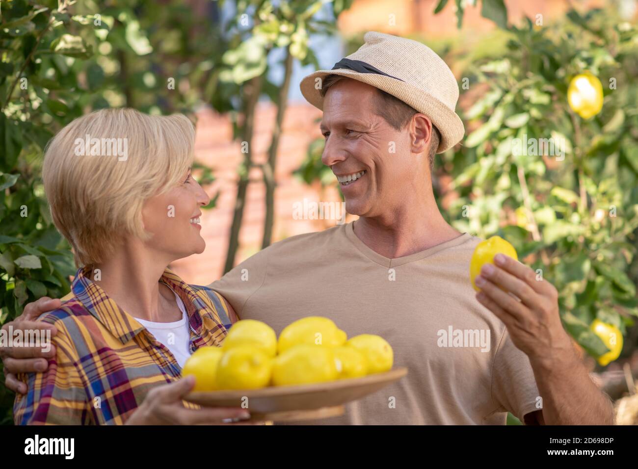 Lächelndes Paar hält Teller mit Zitronen im Garten Stockfoto