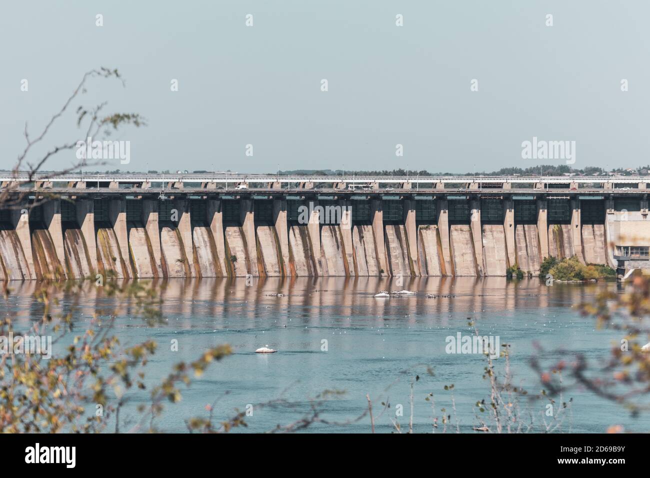 DneproGes am sonnigen Tag Nahsicht mit Reflexion im Wasser. Wasserkraftwerk am Fluss Dnjepr in Zaporozhye, Ukraine. Blick von Khortyzja i Stockfoto