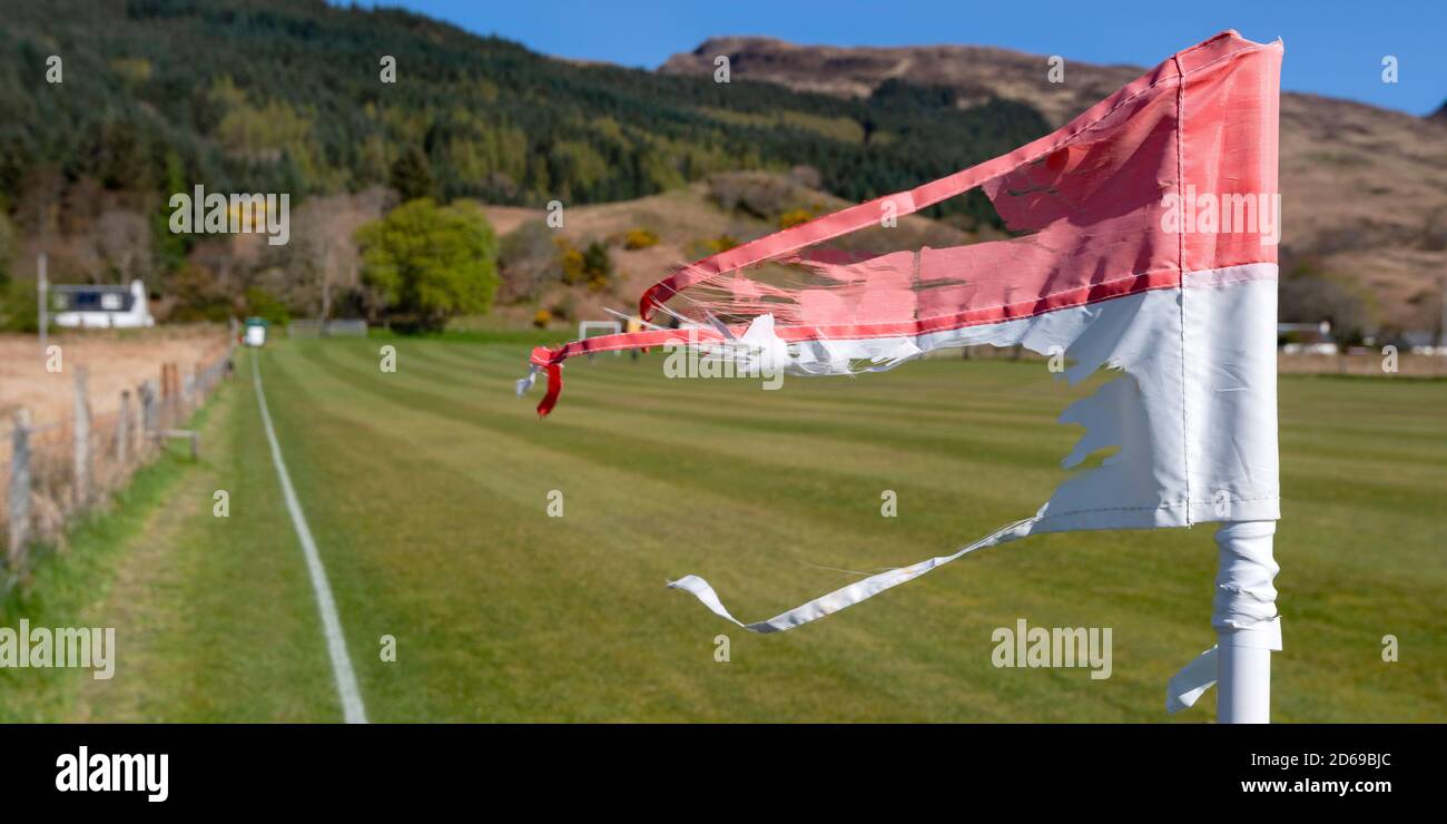 Eine windgepeitschte und zerrissene Eckflagge am Kirkton Ground, dem alten Zuhause des Kinlochshiel Shinty Club im Westen Schottlands. Stockfoto