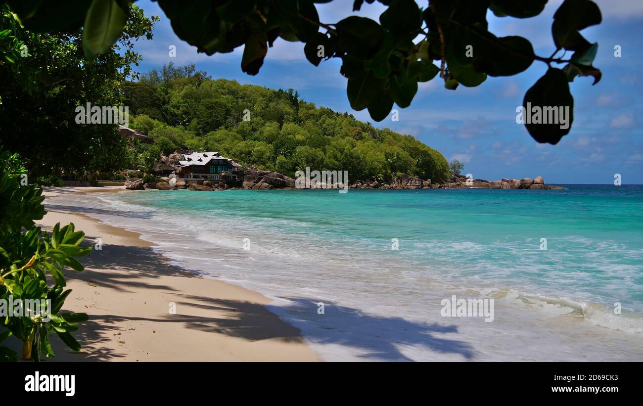 Tropischer Strand Anse Takamaka an der Westküste von Mahe, Seychellen mit türkisfarbenem Wasser, Regenwald und luxuriösem Ferienort. Stockfoto