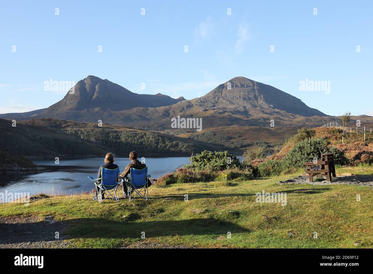 Zwei Personen genießen die Aussicht auf die Quinag Range, die über Loch A' Chàirn Bhàin, Assynt, NW Highlands of Scotland, UK, betrachtet wird Stockfoto