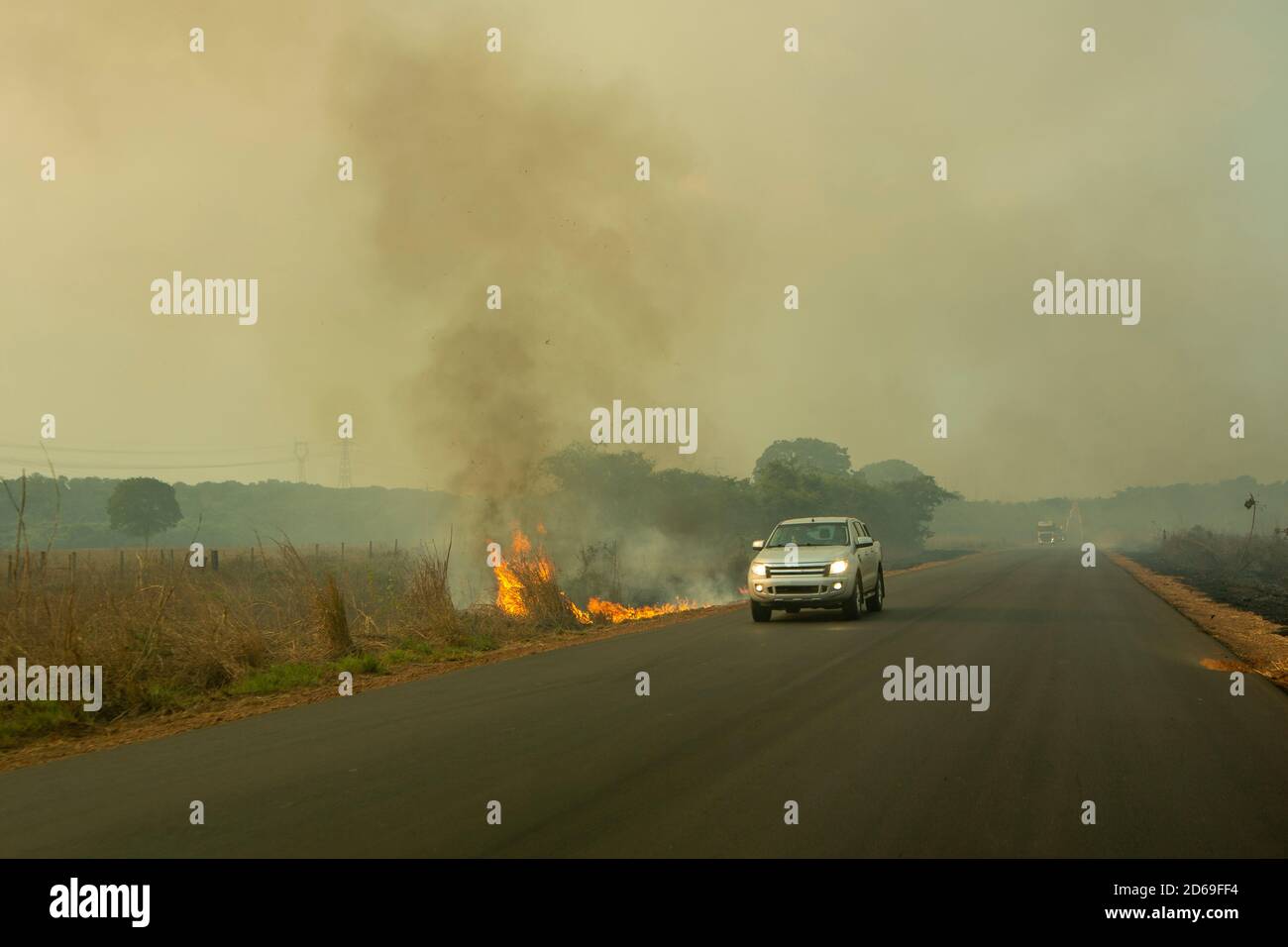 Feuer und Rauch auf BR 163 Straße auf Amazon während der Trockenzeit und verschwommenes Auto fahren schnell in der Nähe der Flammen. Para-Staat, Brasilien. Konzept der Umgebung. Stockfoto