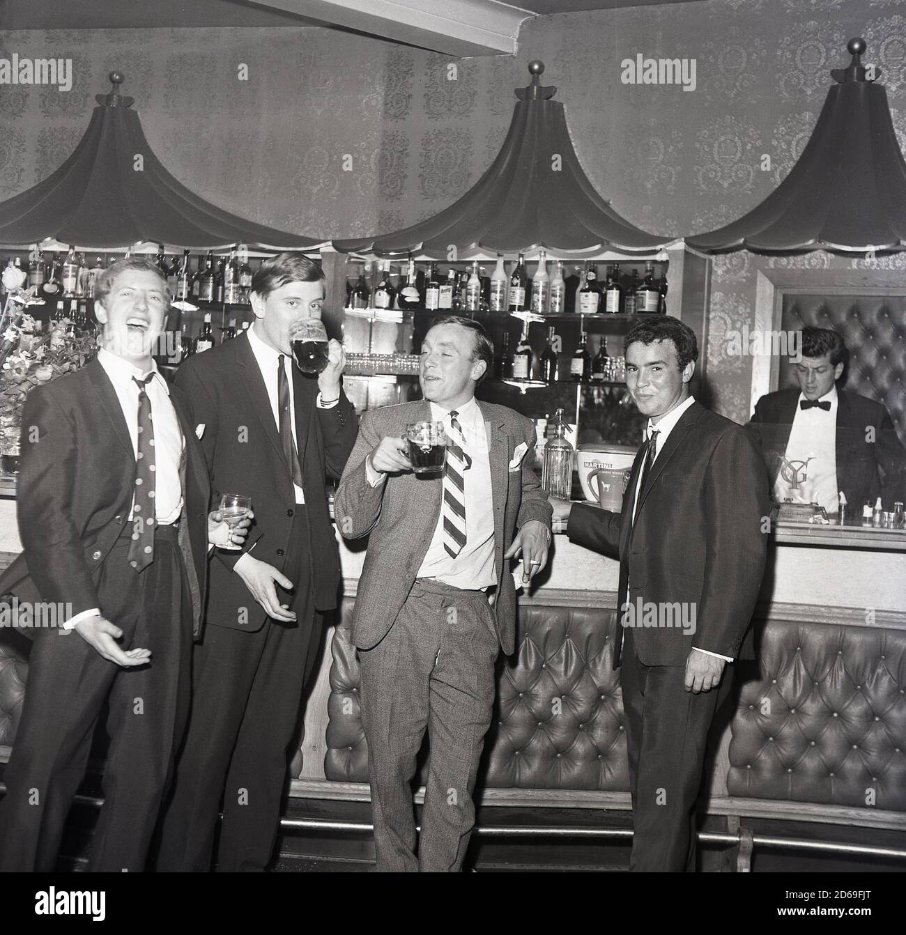 1960er, historisch, vier Männer in Anzügen, stehen an einer Bar, genießen einen Drink, Pints of Bitter und mit gutem Lachen, England, Großbritannien. Stockfoto