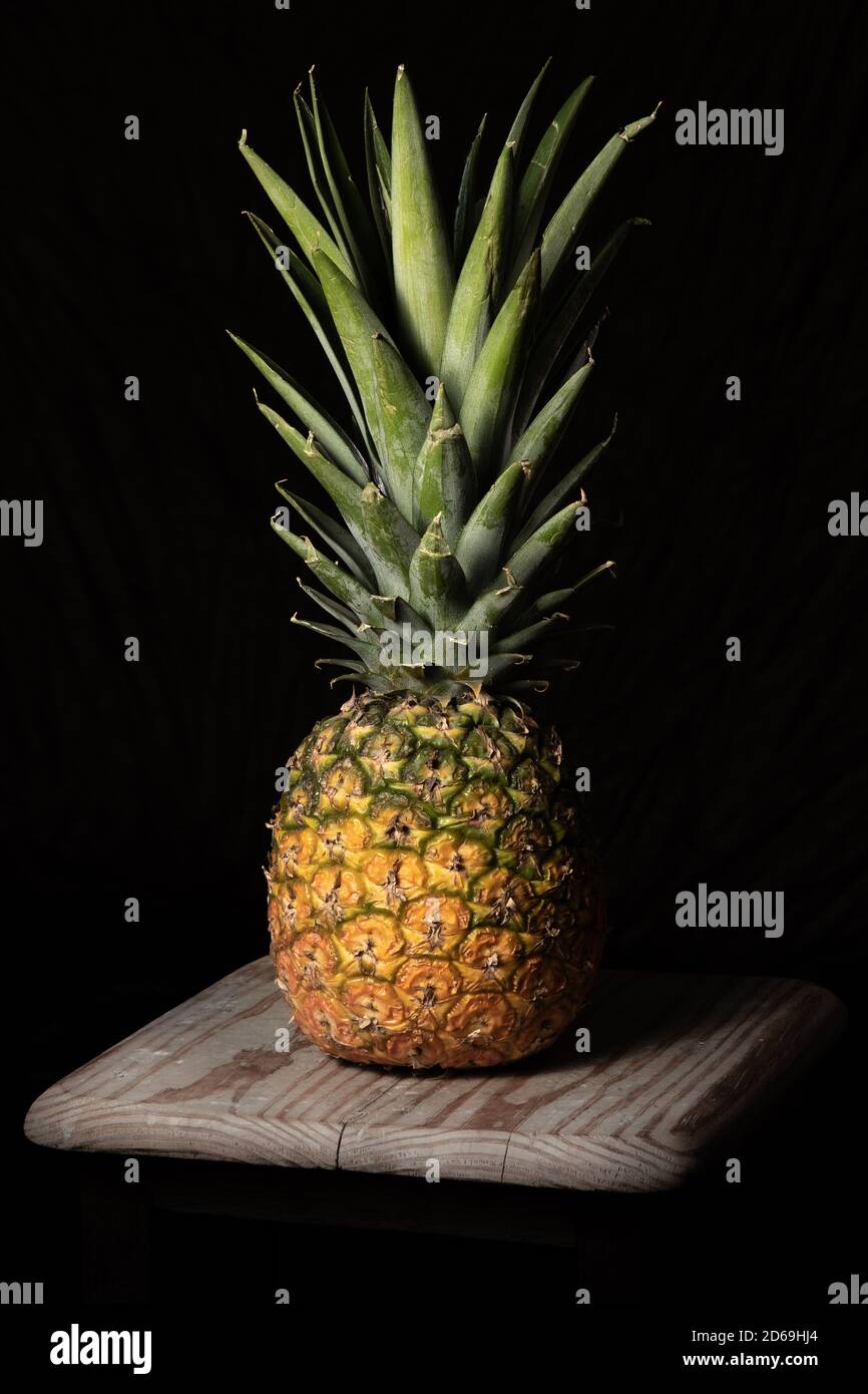 Stillleben Low-Key Schuss Ananasfrucht auf einem rohen Holz Oberfläche Stockfoto