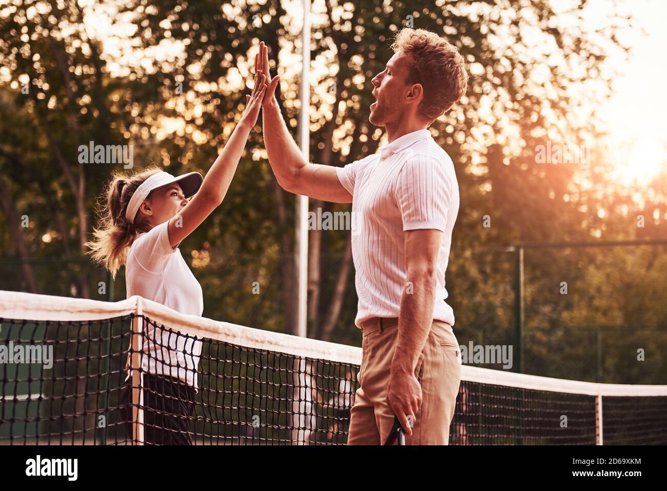 Hohe fünf geben. Zwei Personen in Sportuniform spielen gemeinsam Tennis auf dem Platz Stockfoto