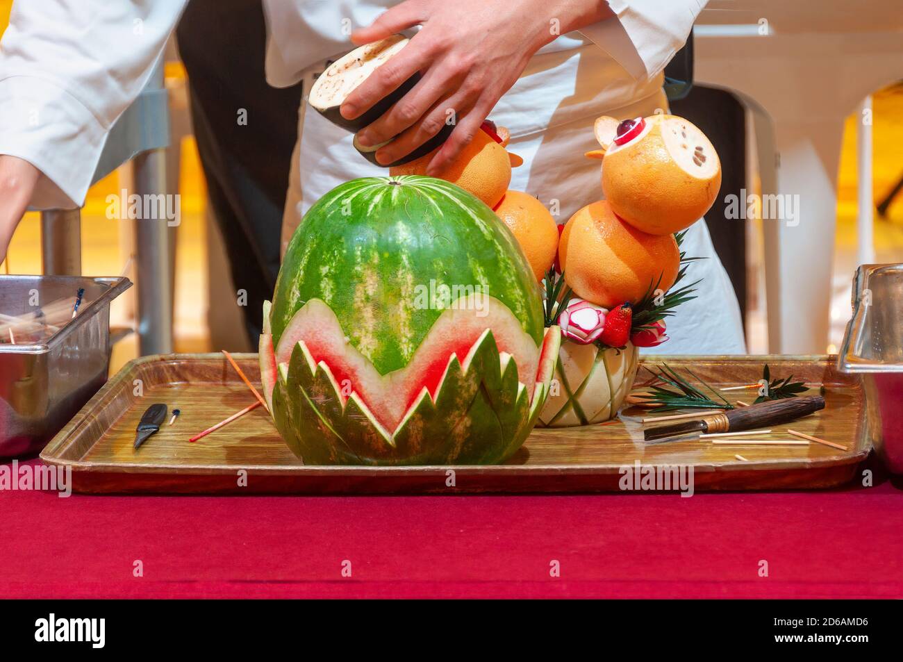 Koch macht Essen schnitzen mit Wassermelone, Orangen und Auberginen. Stockfoto