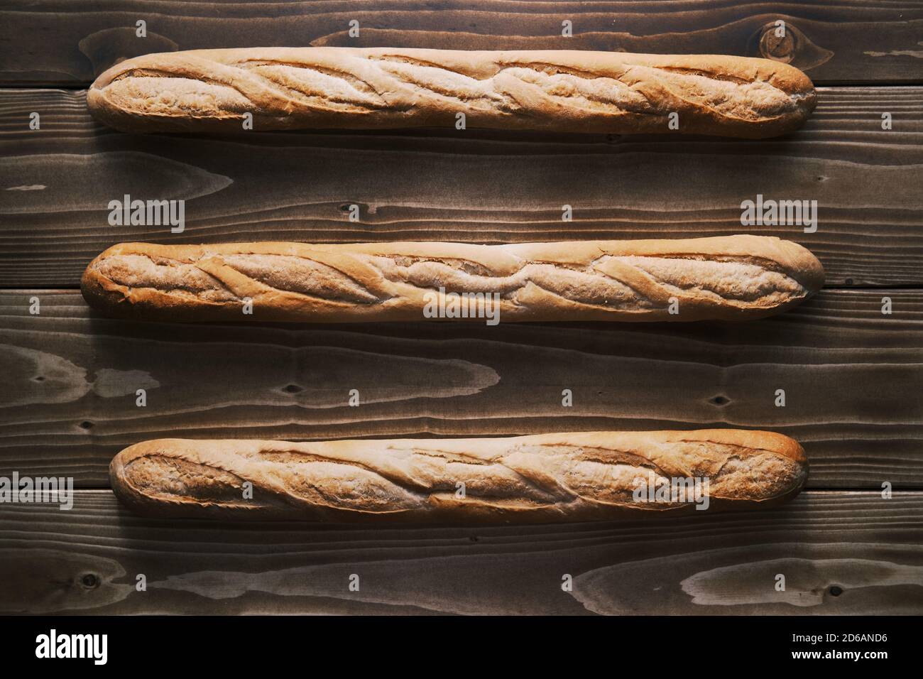 Vertikale Aufnahme eines drei frischen Französisch Baguette auf einem Holztisch. Bereit zu essen Stockfoto