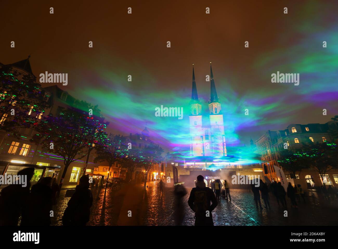 Halle, Deutschland. Oktober 2020. 15. Oktober 2020, Sachsen-Anhalt, Halle (Saale): Passanten sehen künstlich erzeugte Auroren auf dem Hallmarkt mit Laserstrahlen und Nebel. Die Lichtinstallation 'Borealis' des Schweizer Künstlers Dan Archer ist Teil des diesjährigen Silver Salt Science and Media Festivals. Unter dem Motto "Home Earth" findet sie vom 14. Bis 18. Oktober in Halle (Saale) statt. Foto: Jan Woitas/dpa-Zentralbild/dpa Quelle: dpa picture Alliance/Alamy Live News Stockfoto