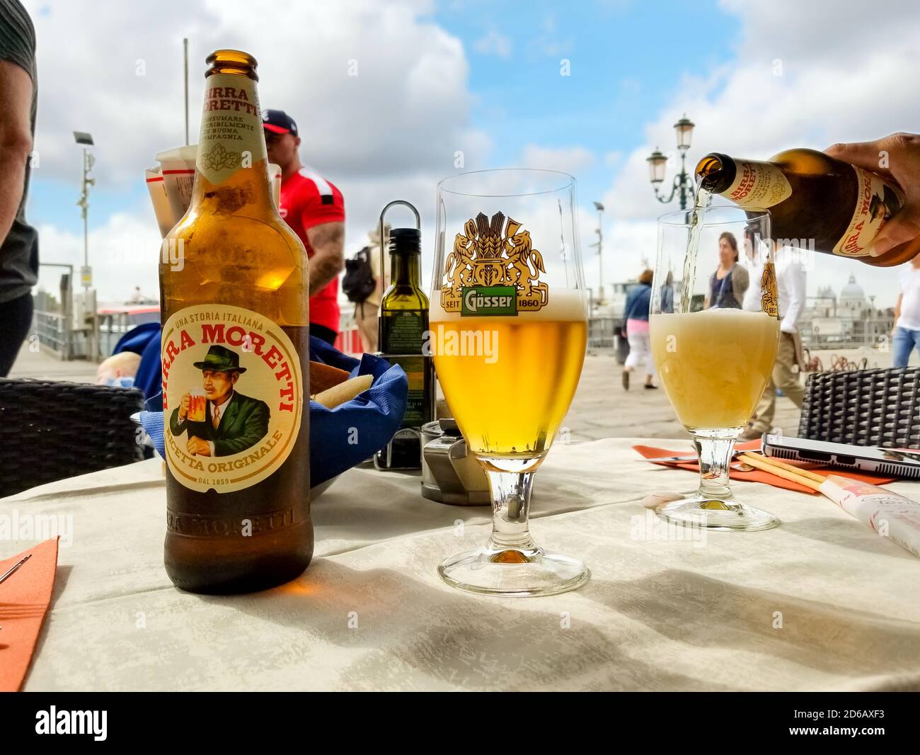 Eine weibliche Hand gießt ein italienisches Bier in ein Glas aus einer Flasche in einem Straßencafé am Canale Grande in Venedig, Italien Stockfoto