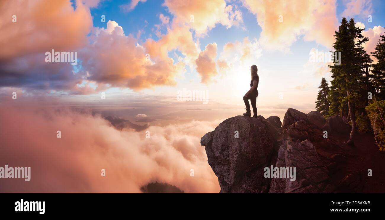 Abenteuerliche weibliche Wanderin auf einem Berg mit Wolken Stockfoto