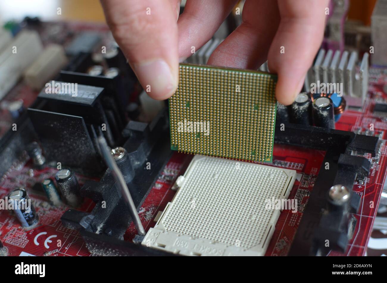 Eine Hand, die eine CPU (Prozessor-Chip) von der Hauptplatine eines alten Computers entfernt. Stockfoto