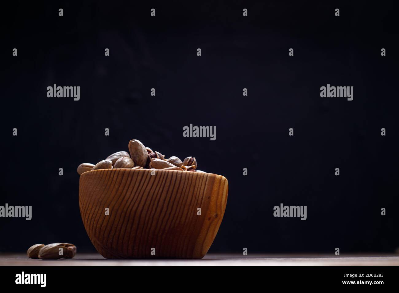 Pistazien in einem Holzbecher auf dunklem Hintergrund. Leerzeichen für Text Stockfoto