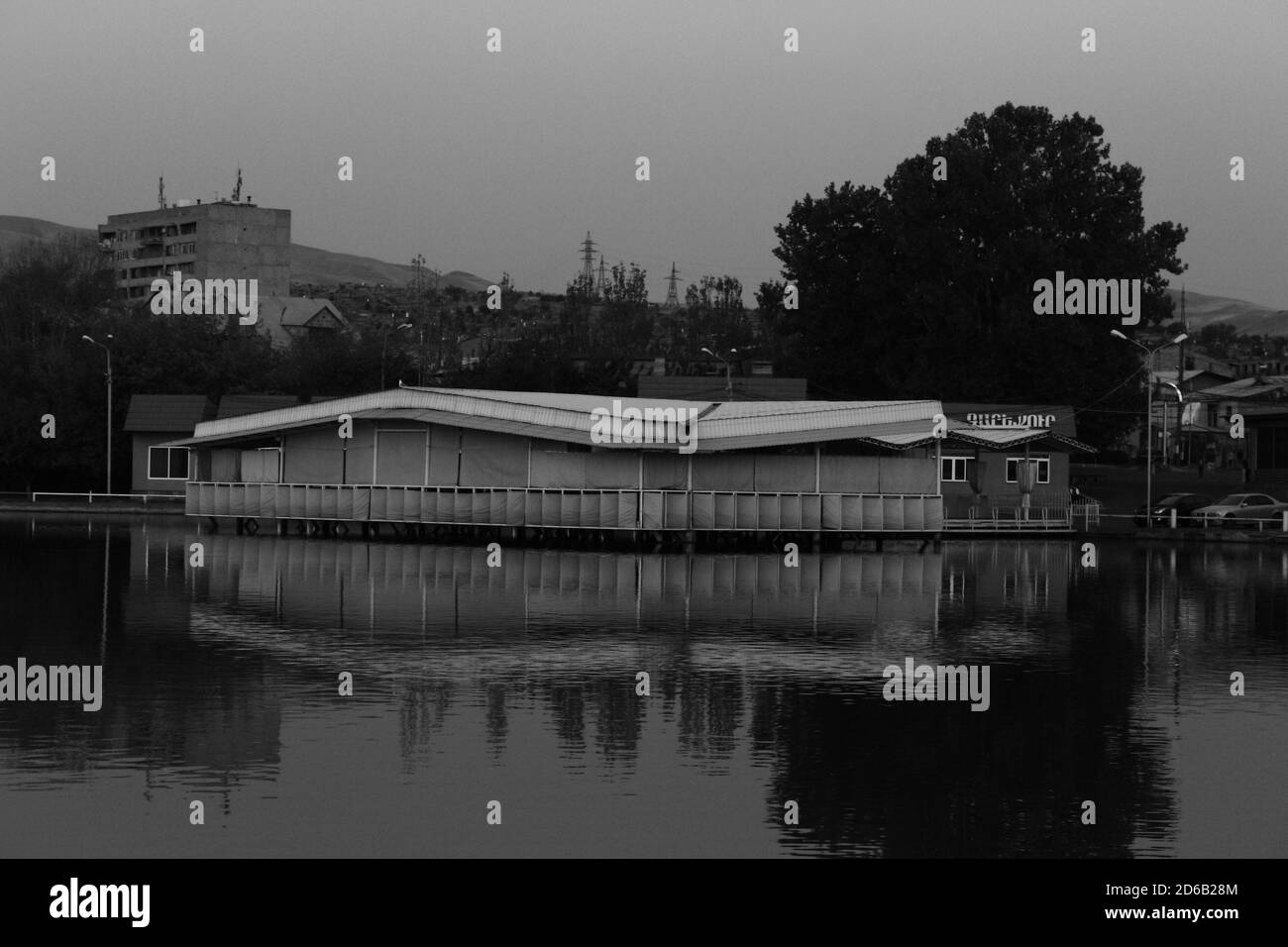 Erstaunliche Graustufen Aufnahme einer Stadt mit Küstenbau Reflexionen Auf ruhigem Seewasser Stockfoto