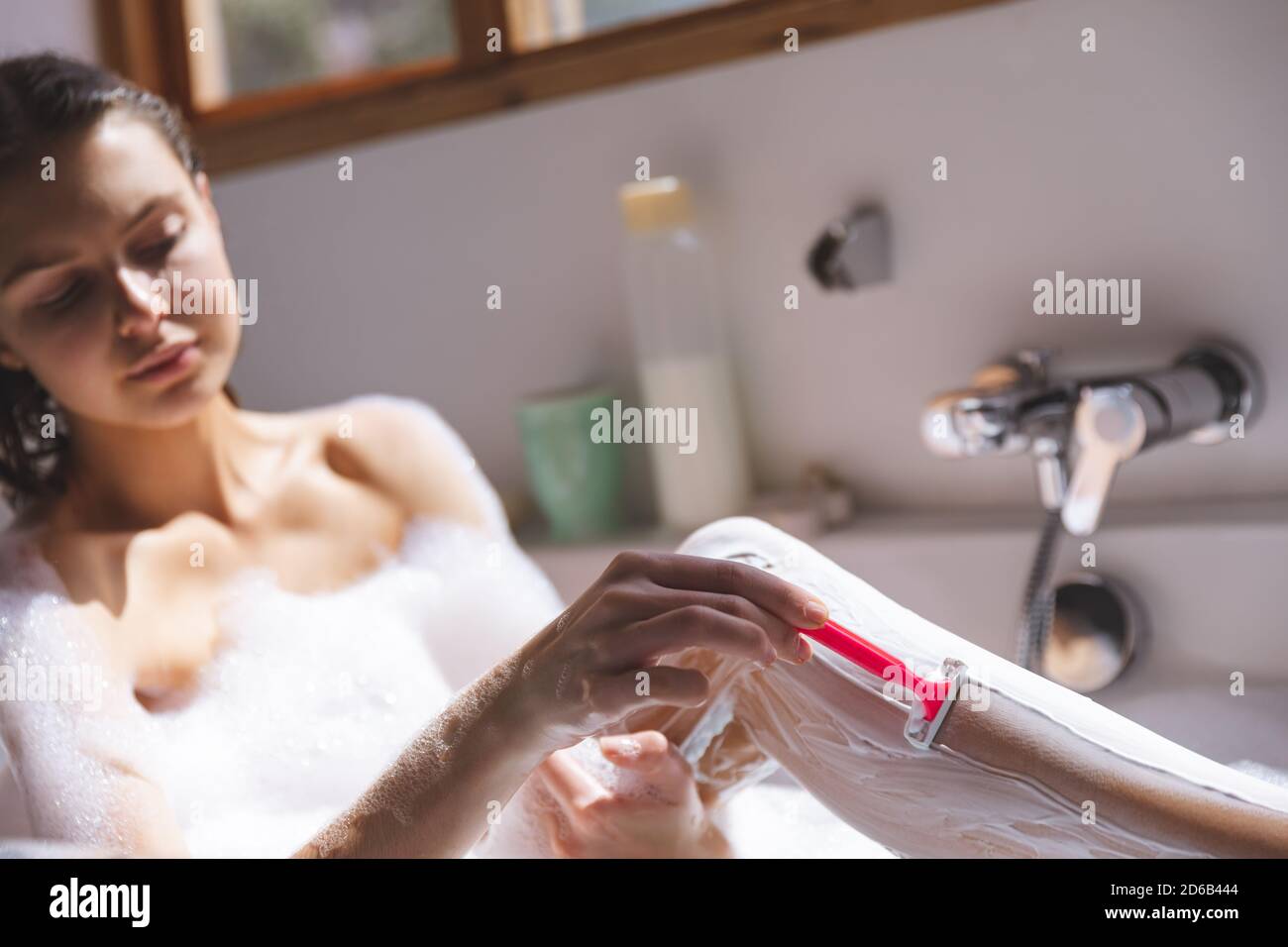 Frau rasieren ihre Beine in der Badewanne Stockfoto