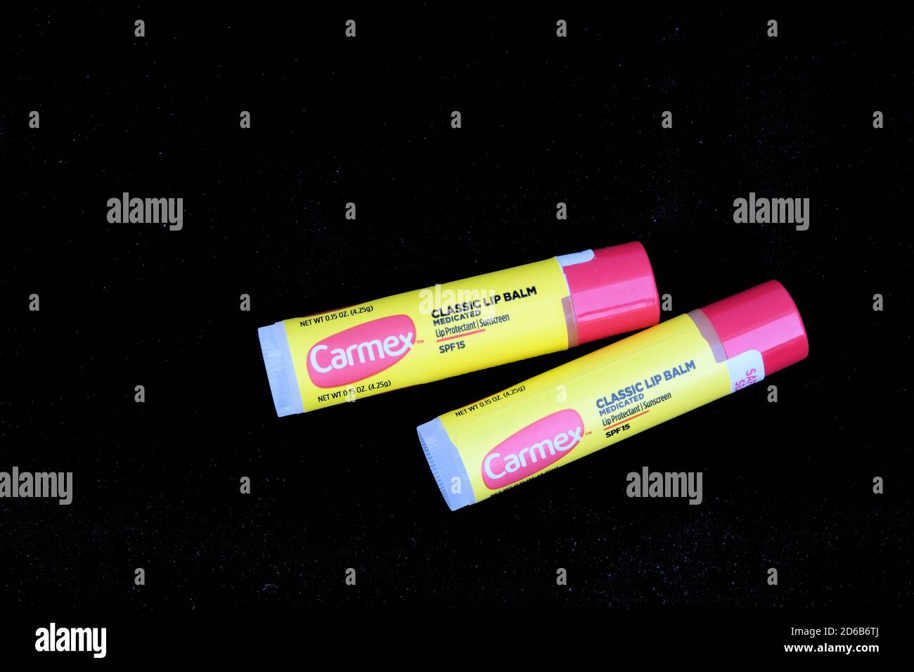 Zwei Carmex original medizinische Lippenbalsam-Sticks mit SPF 15 auf schwarzem Hintergrund; Lippenschutz. Stockfoto