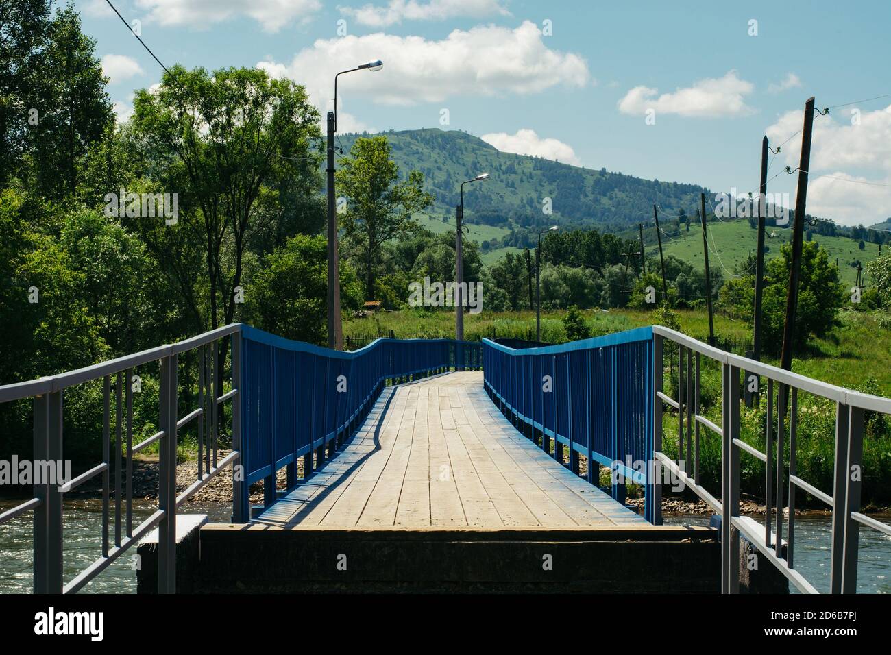 Menschliche Interaktion mit Wildtieren. Eine Brücke über einen Gebirgsfluss zwischen den Hügeln. Elektrische Pfosten. Straßenbeleuchtung. Stockfoto