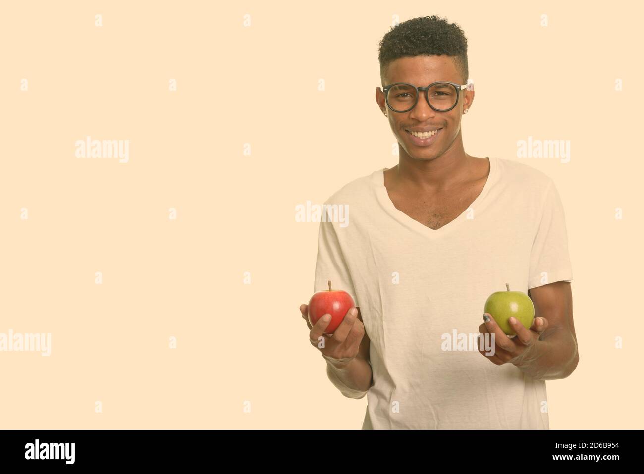 Junger glücklicher afrikanischer Mann mit rotem und grünem Apfel Stockfoto