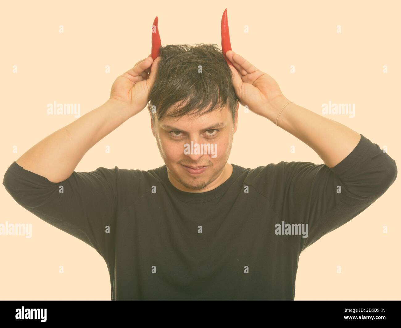 Studio shot Verrückter kaukasischen Mann mit rotem Paprika wie Hörner Stockfoto