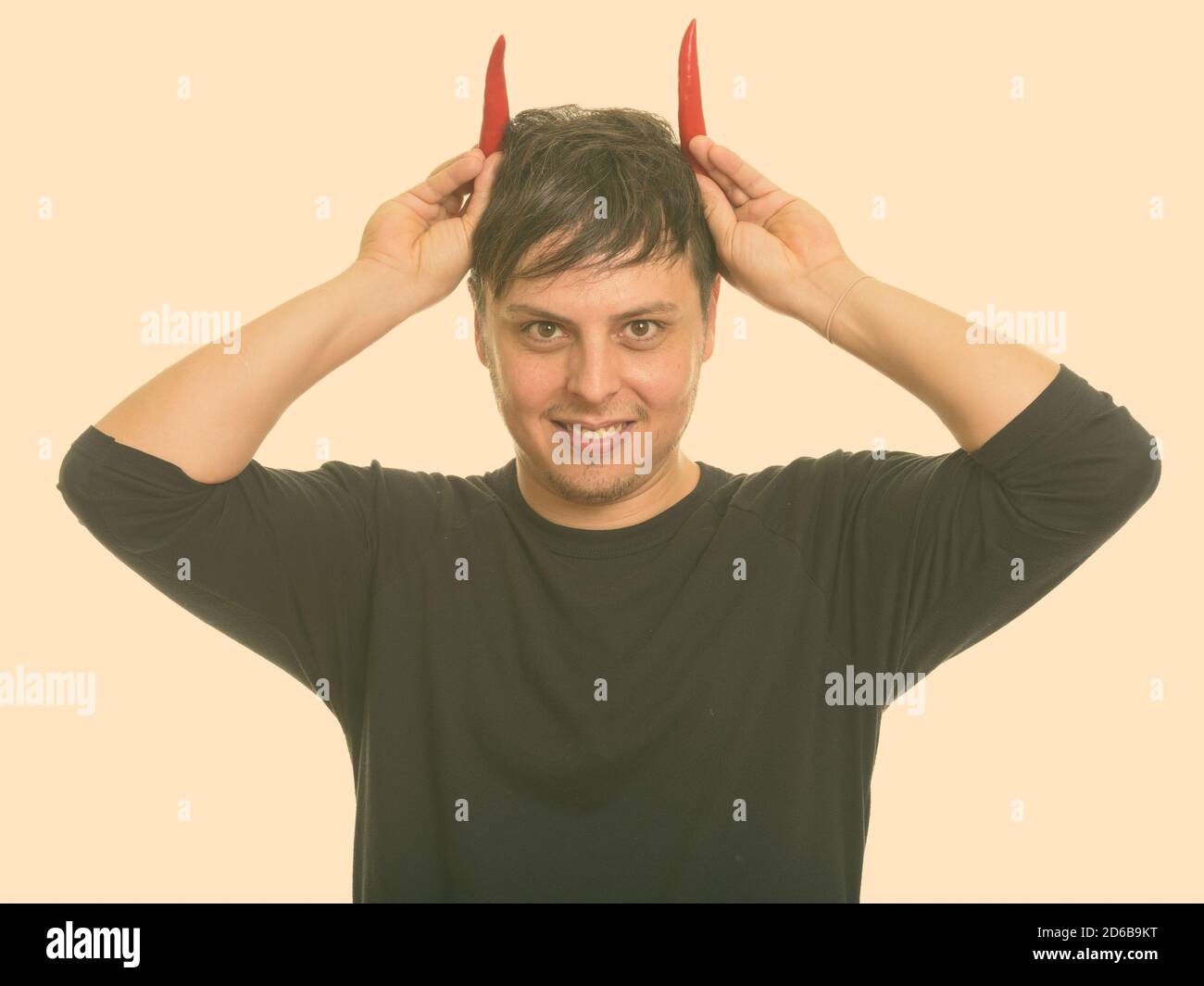 Studio Schuss von verrückten kaukasischen Mann mit roten Paprika als Lächelnde Hörner Stockfoto