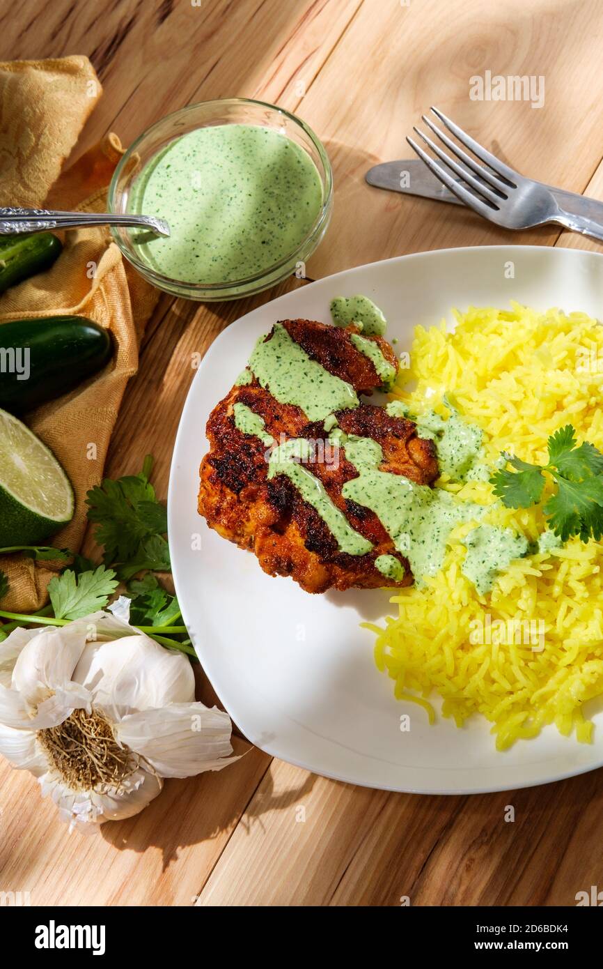 Peruanische Hähnchenschenkel mit Aji verde grüne Koriander Sauce und Gelber Reis Stockfoto