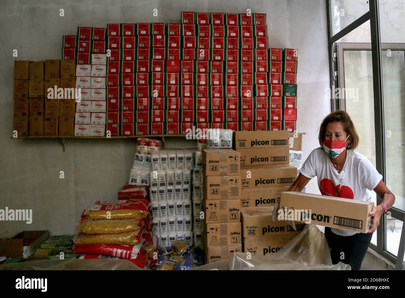 Beirut, Libanon. Oktober 2020. Die 60-jährige Lina Boubis, die als Mutter der Revolution bezeichnet wird, trägt eine Gesichtsmaske mit den Farben der libanesischen Flagge und arbeitet an der Verteilung von Lebensmittelpaketen für bedürftige Menschen in einem Lagerhaus, das von regierungsfeindlichen Aktivisten in Beirut eingerichtet wurde. Am 17. Oktober 2019 gingen Tausende von Menschen im Libanon auf die Straße, um gegen neue Steuern und weit verbreitete Korruption in der herrschenden Klasse zu protestieren. Quelle: Marwan Naamani/dpa/Alamy Live News Stockfoto