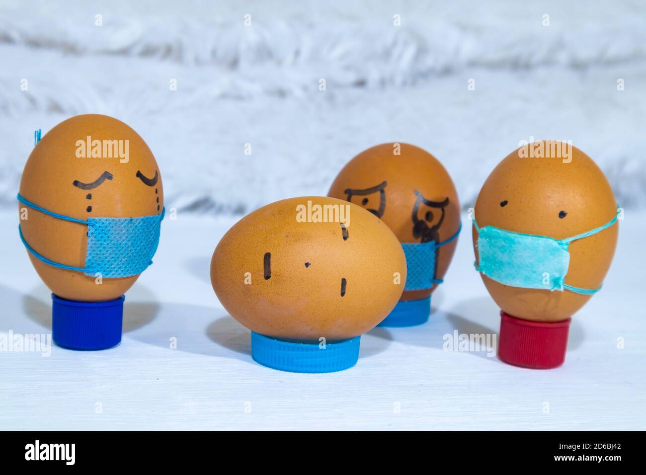 Mehrere bemalte Eier tragen Masken, Trauer um einen Toten, der keine Maske trägt. Spaß Indoor-Aktivitäten mit Kindern. Stockfoto