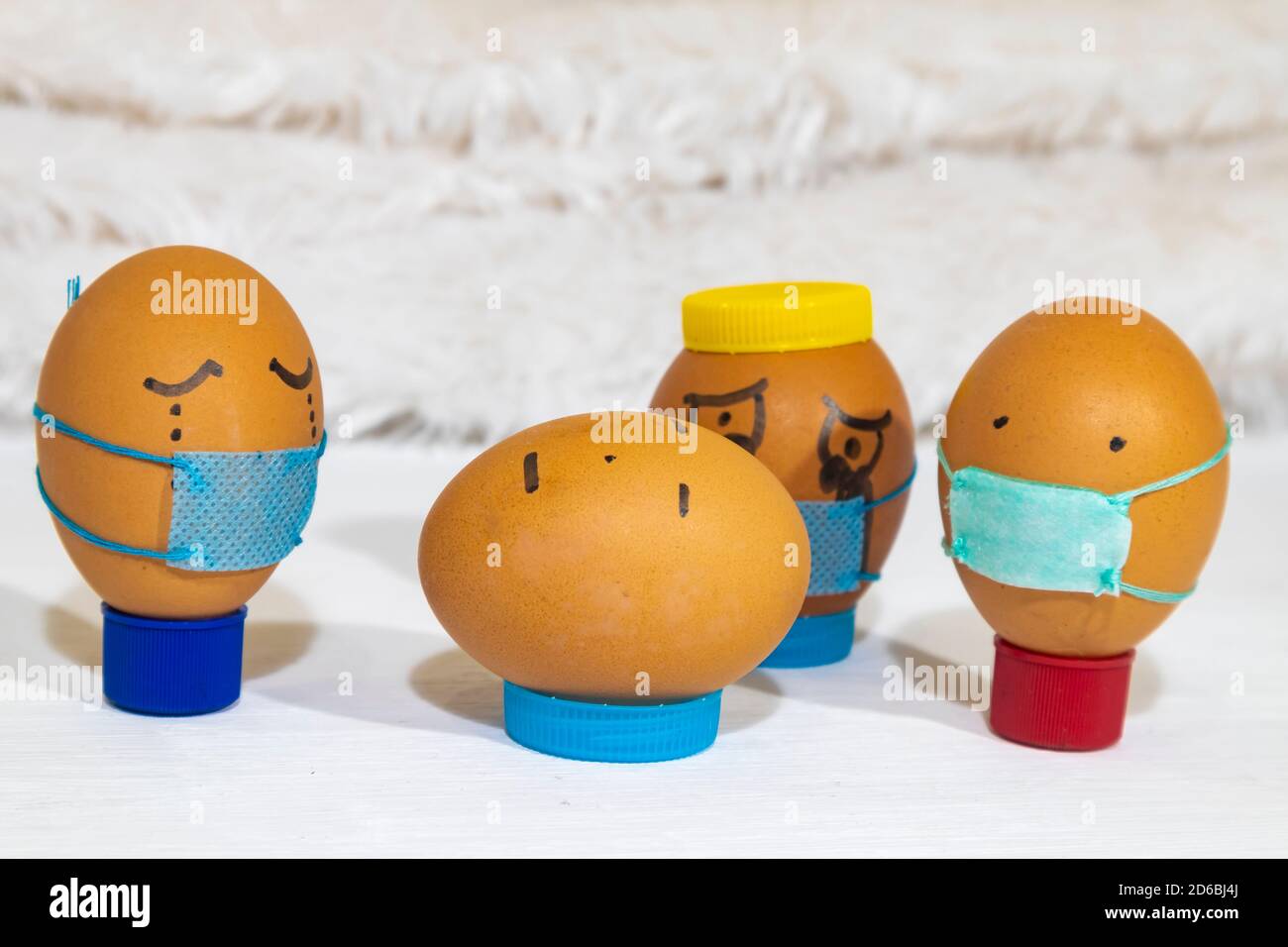 Mehrere bemalte Eier tragen Masken, Trauer um einen Toten, der keine Maske trägt. Spaß Indoor-Aktivitäten mit Kindern. Stockfoto