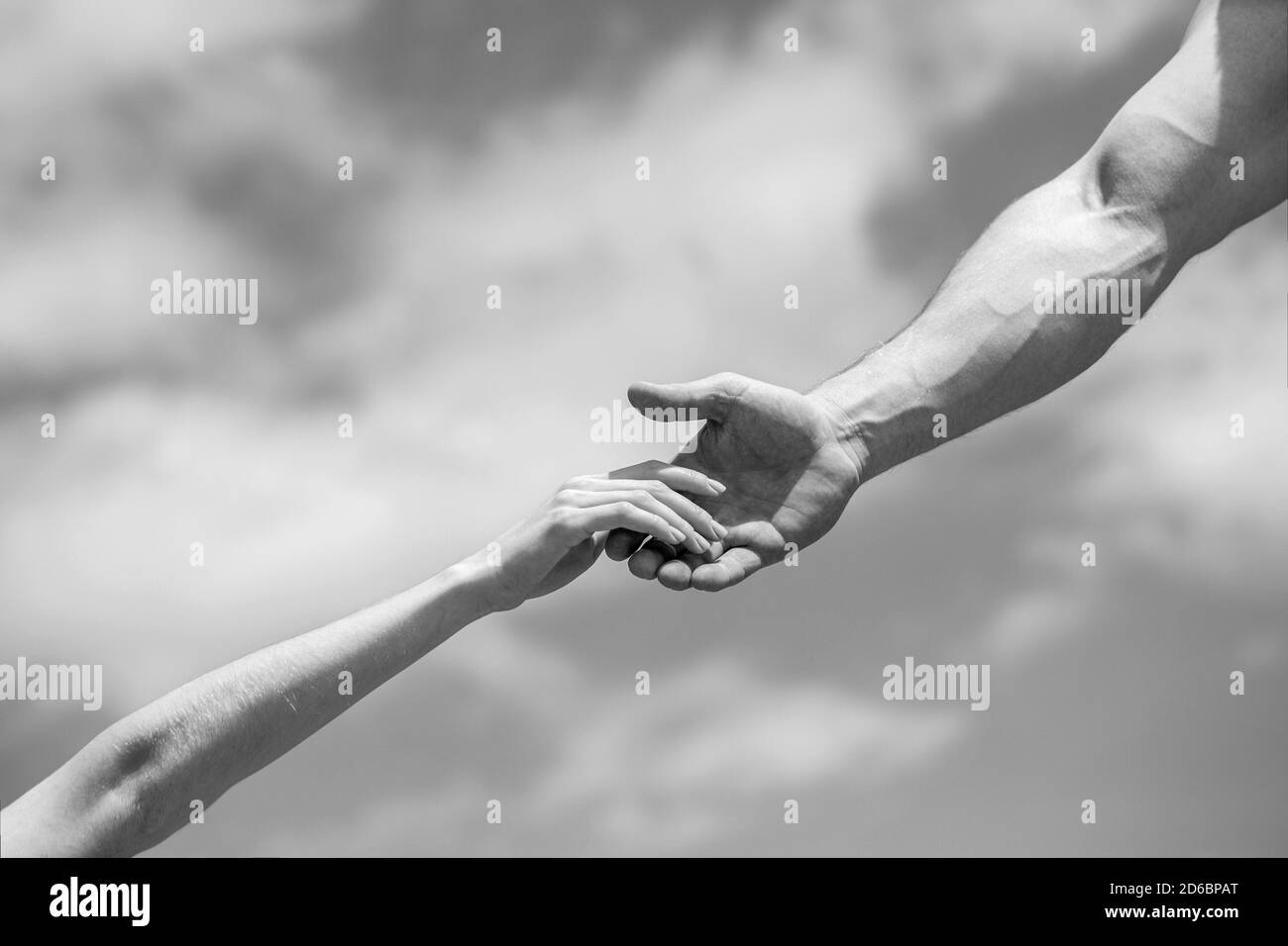 Hände von Mann und Frau auf blauem Himmel Hintergrund. Eine helfende Hand geben. Solidarität, Mitgefühl und Nächstenliebe, Rettung. Schwarz und Weiß Stockfoto