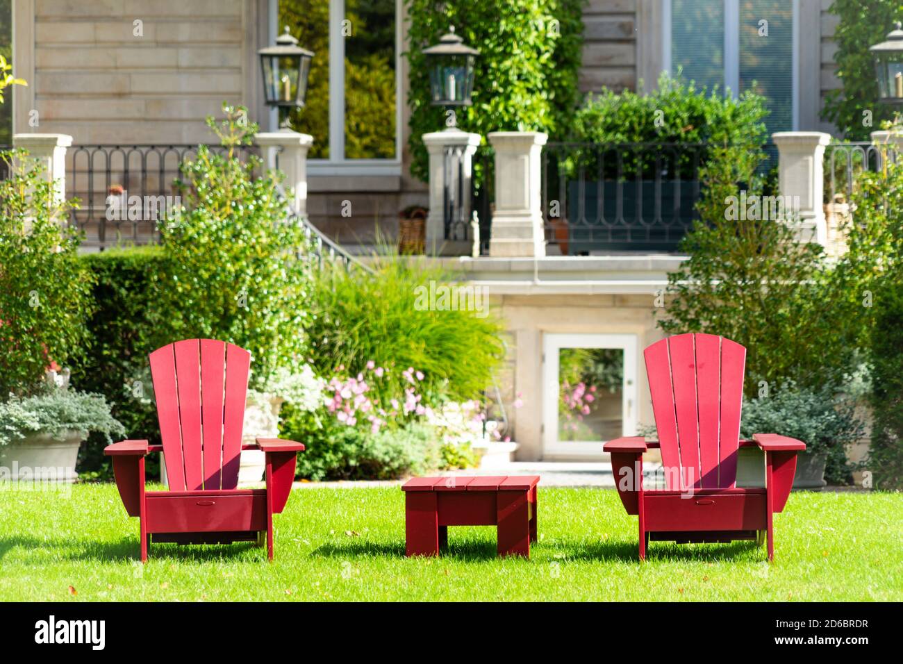 Rote Gartenmöbel auf einer Wiese mit einem stattlichen Herrenhaus Im Hintergrund Stockfoto