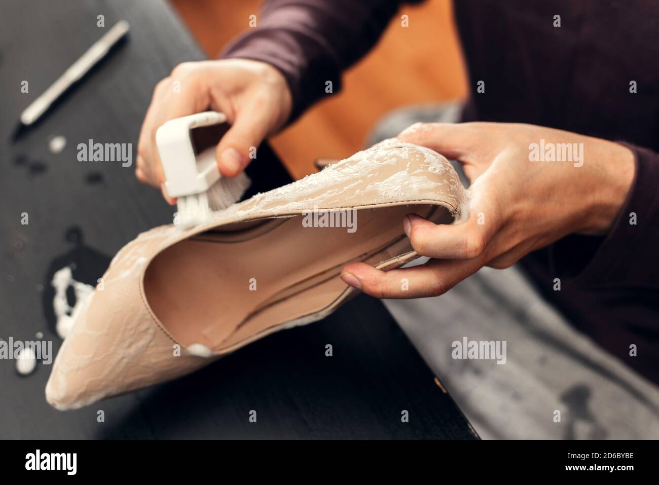 Ein Mann putzt Damenschuhe mit einer Bürste. Reinigen des Schuhs von Schmutz. Stockfoto