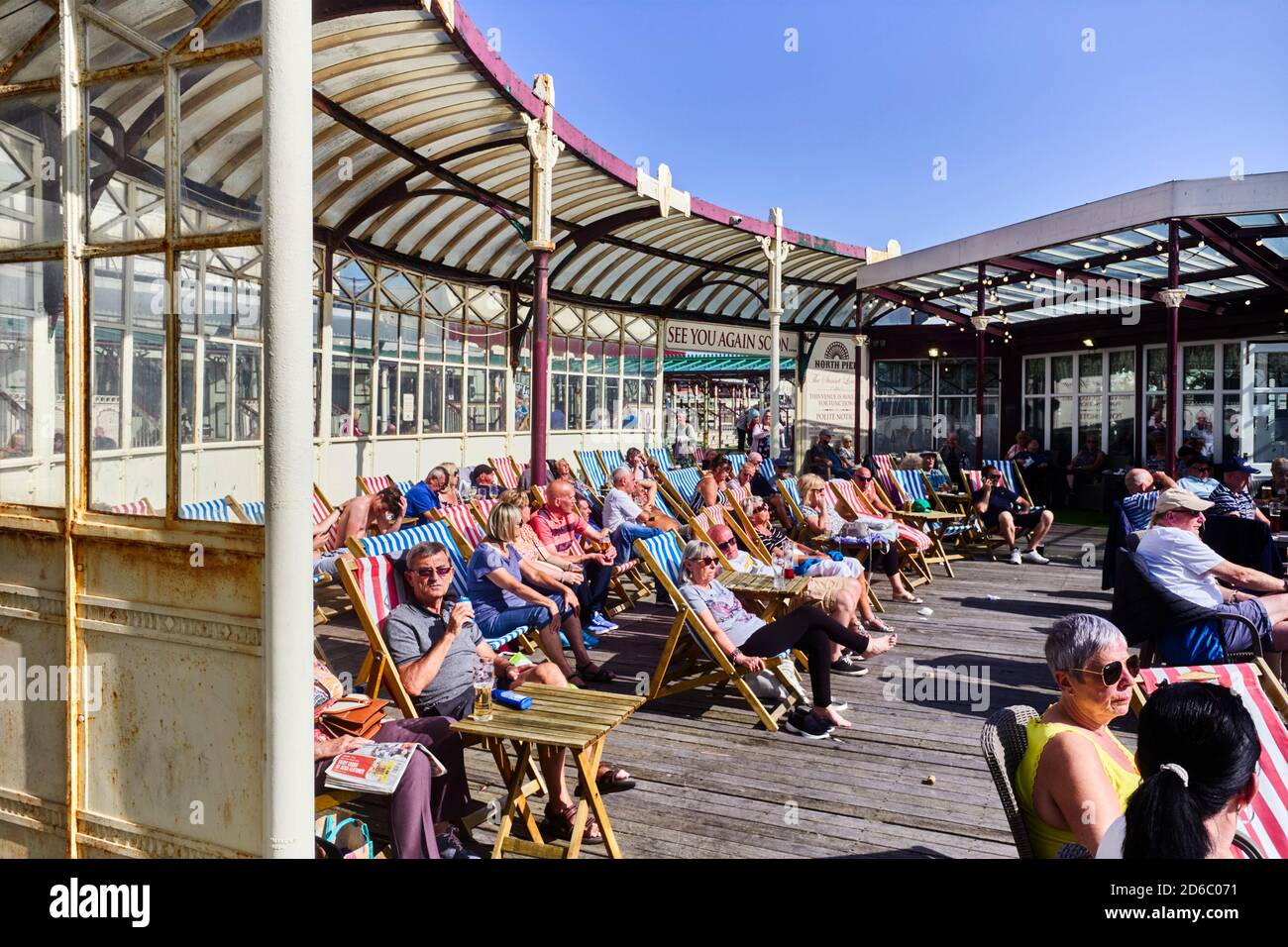 Menschen sitzen in Liegestühlen genießen die Sonne und Live-Musik Am Ende des North Pier in Blackpool Stockfoto