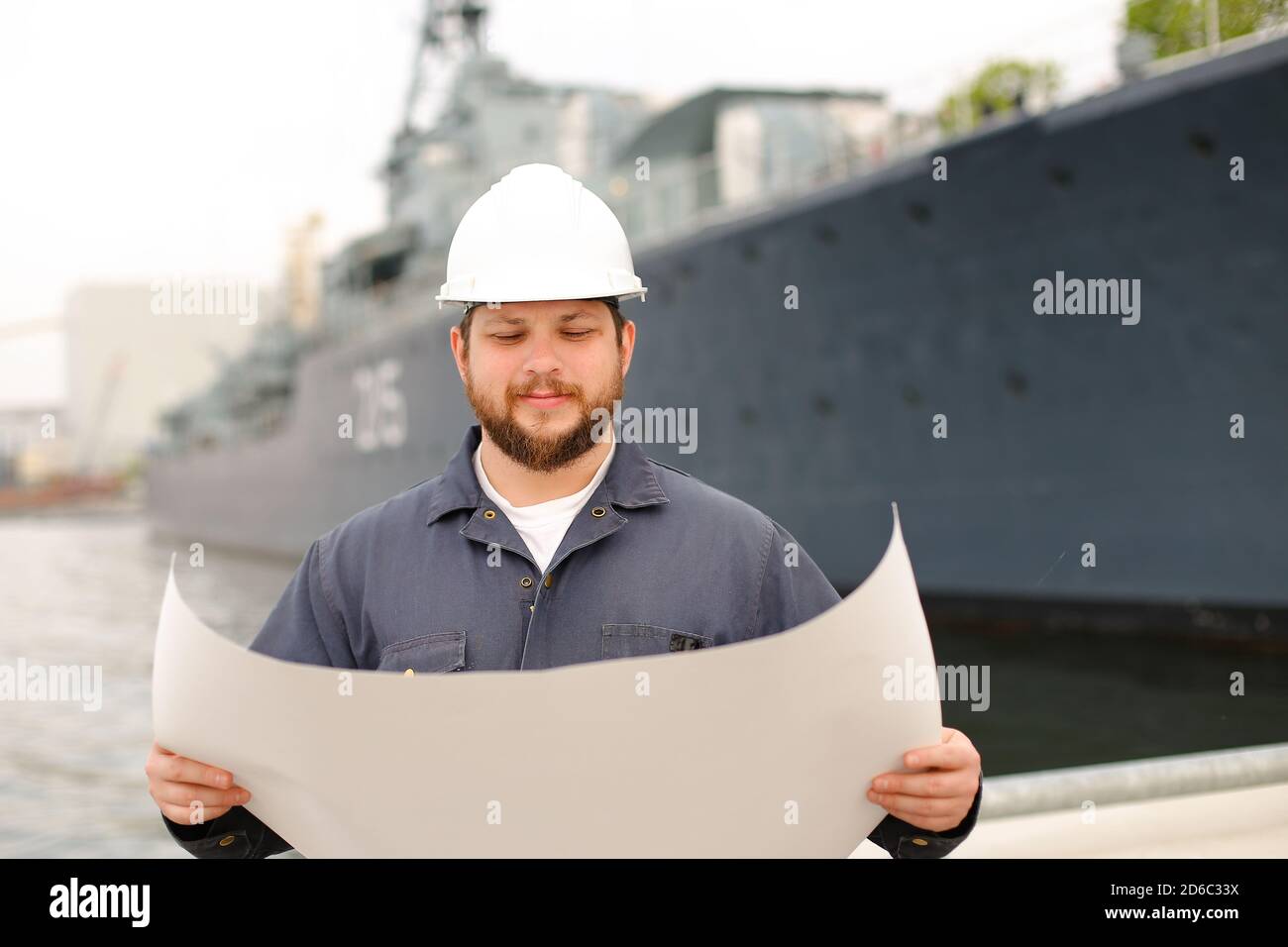 Assistenzingenieur beim Lesen von Dokumenten und beim Stehen in der Nähe des Schiffes. Stockfoto