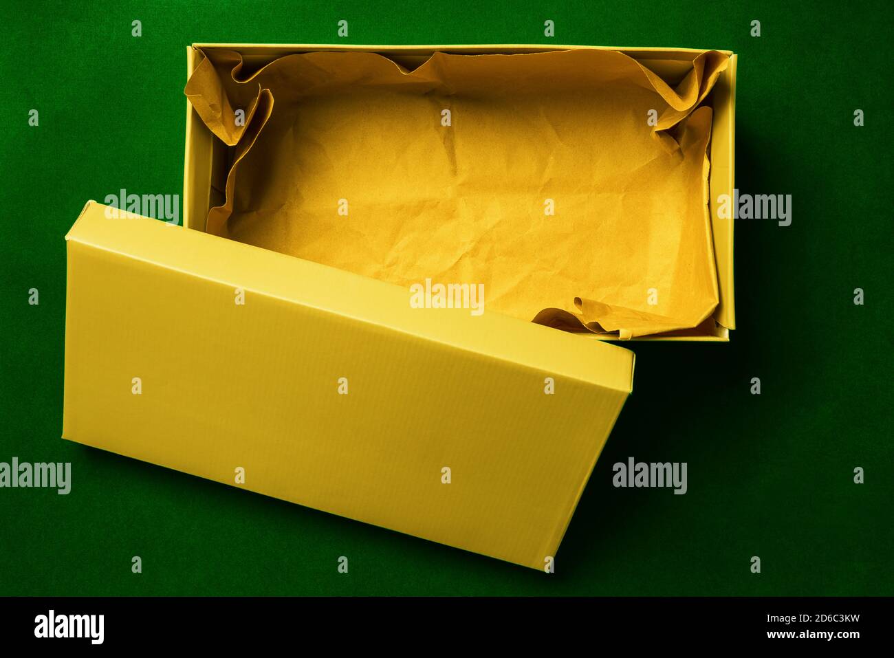 Gelbes Feld auf grünem Hintergrund. Farbkarton Verpackung für den Versand der Ware. Karton für Schuhe oder Geschenk. Draufsicht, flaches Layout Stockfoto