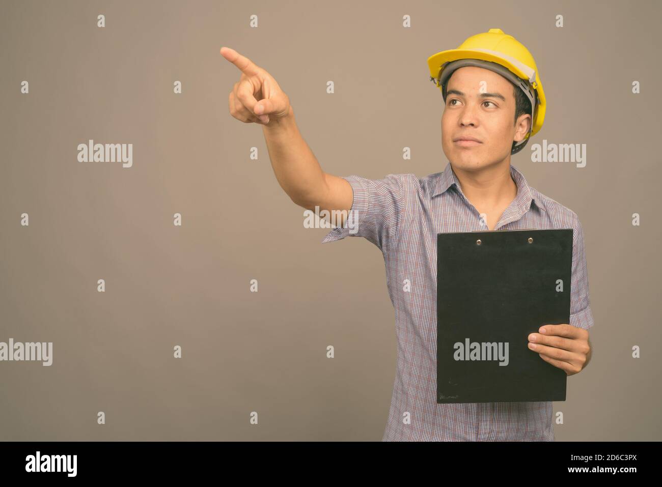 Junge asiatische Geschäftsmann, tragen, hardhat gegen grauer Hintergrund Stockfoto