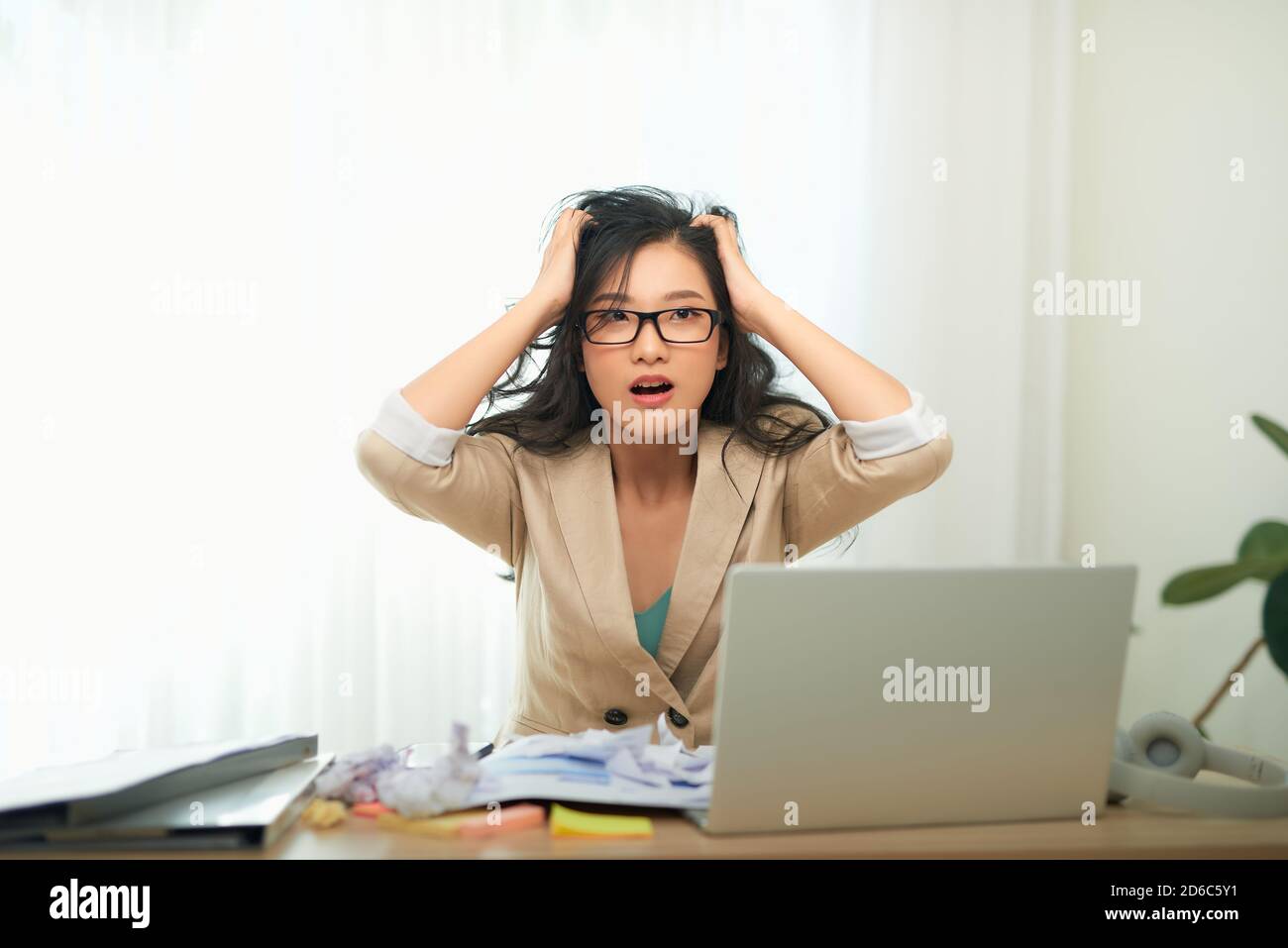 Eine junge Geschäftsfrau sieht gestresst aus, als sie an ihrem Computer arbeitet. Horizontale Aufnahme. Stockfoto