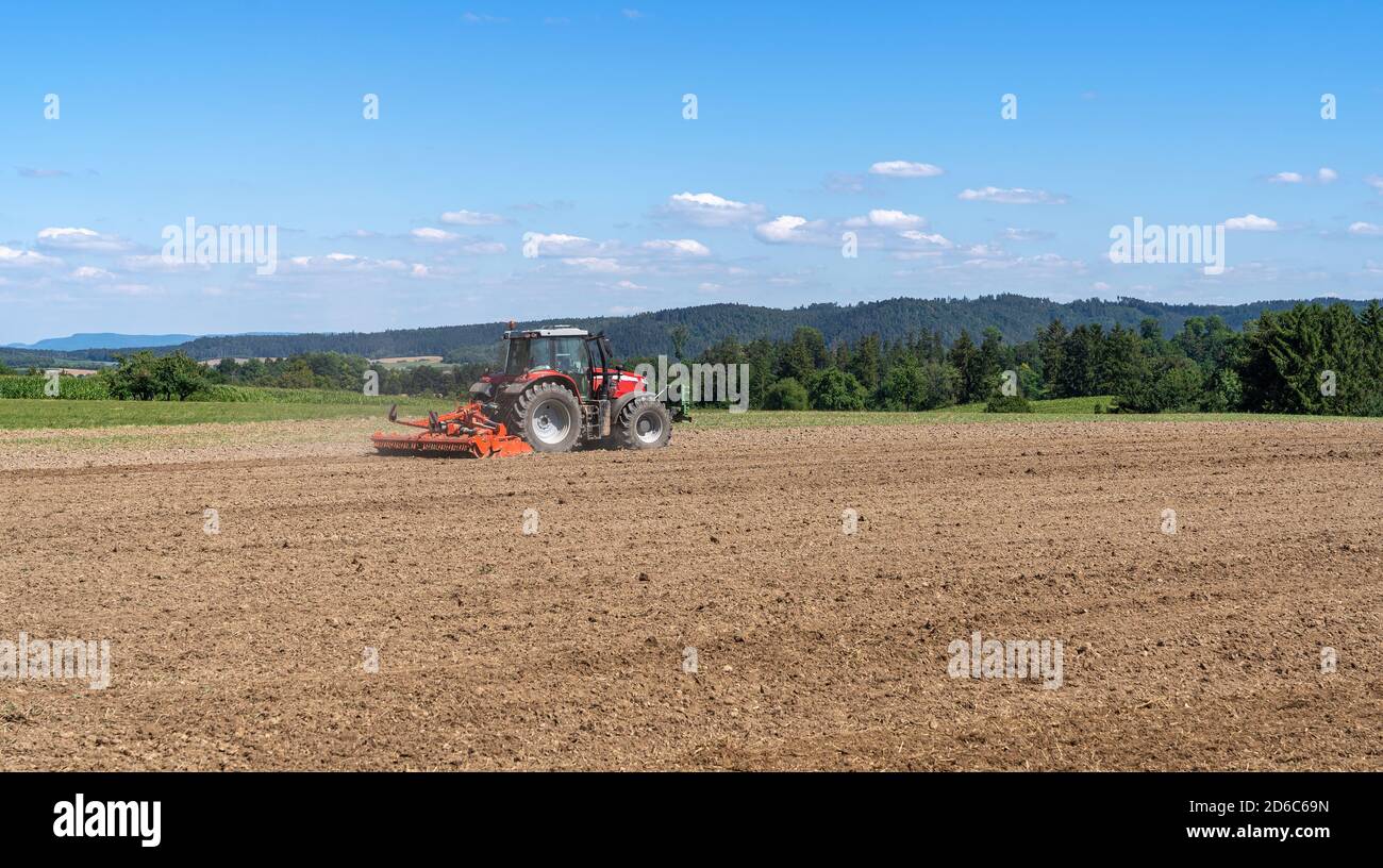 Traktor eggt ein landwirtschaftliches Feld Stockfoto